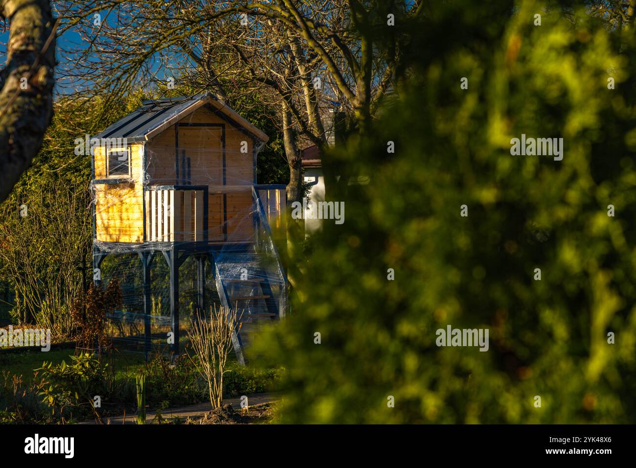 Una casa sull'albero in legno per bambini protetta contro la neve invernale e la pioggia con un foglio di alluminio Foto Stock