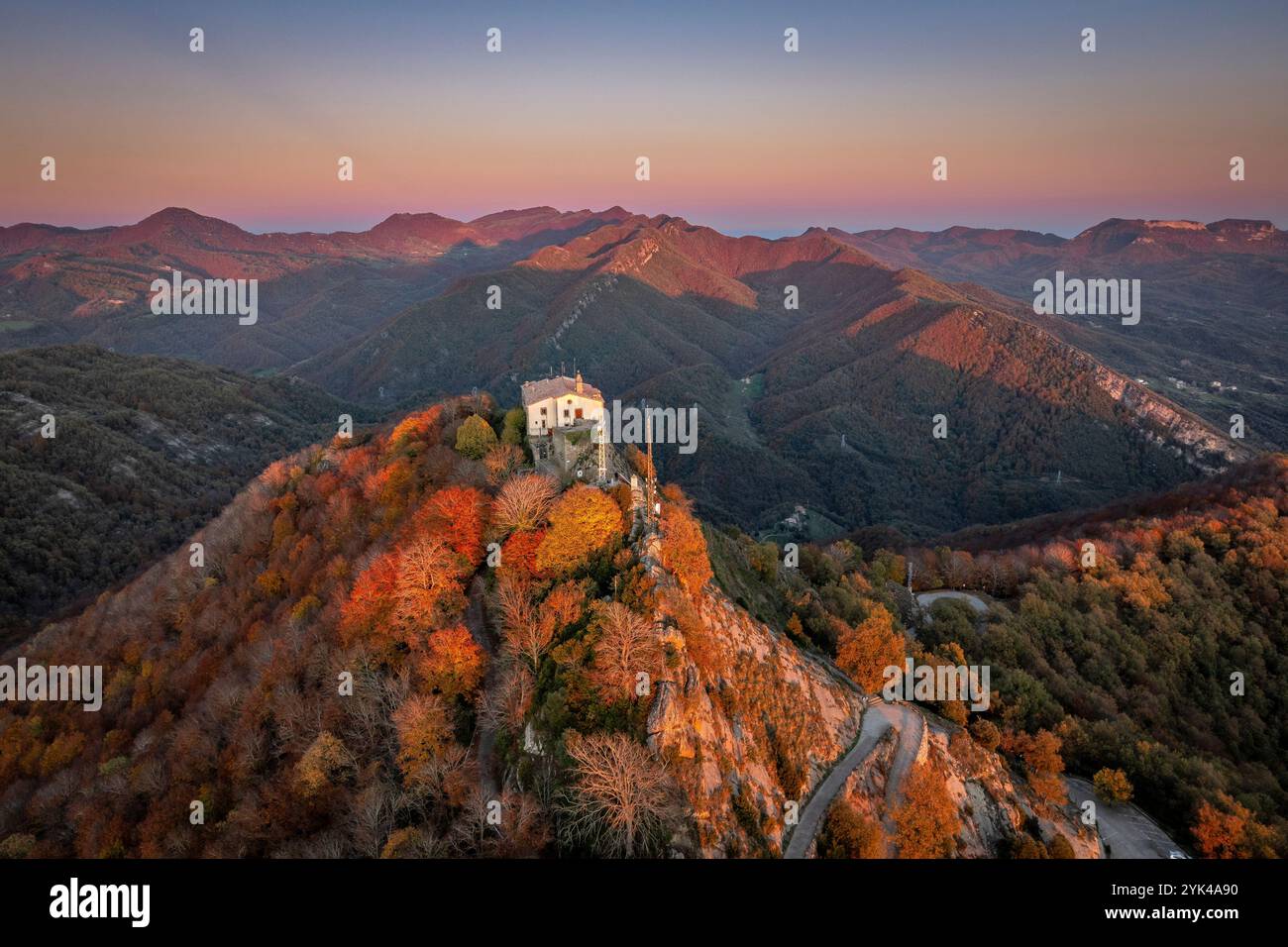 Vista aerea della catena montuosa e del santuario di Bellmunt, al tramonto autunnale con i colori ocra della foresta di faggi (Osona, ​​Catalonia, Spagna) Foto Stock