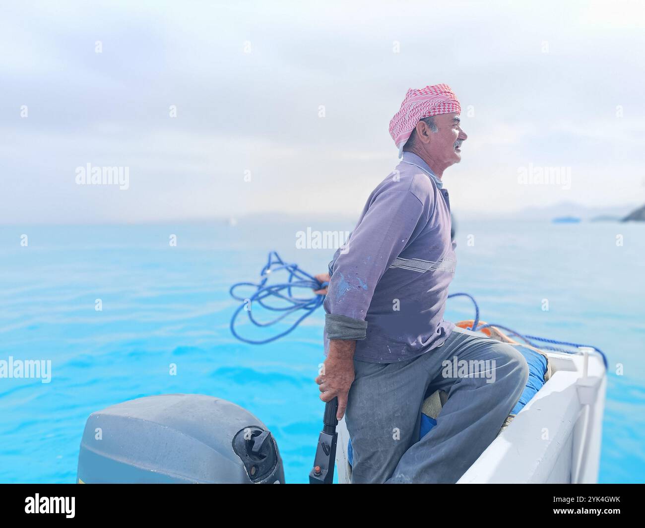Old Sailor in the Sea Riding and Sailing with HIS Boat un vecchio marinaio con un bianco con baffi bianchi che indossa una sciarpa beduina sulla testa Foto Stock