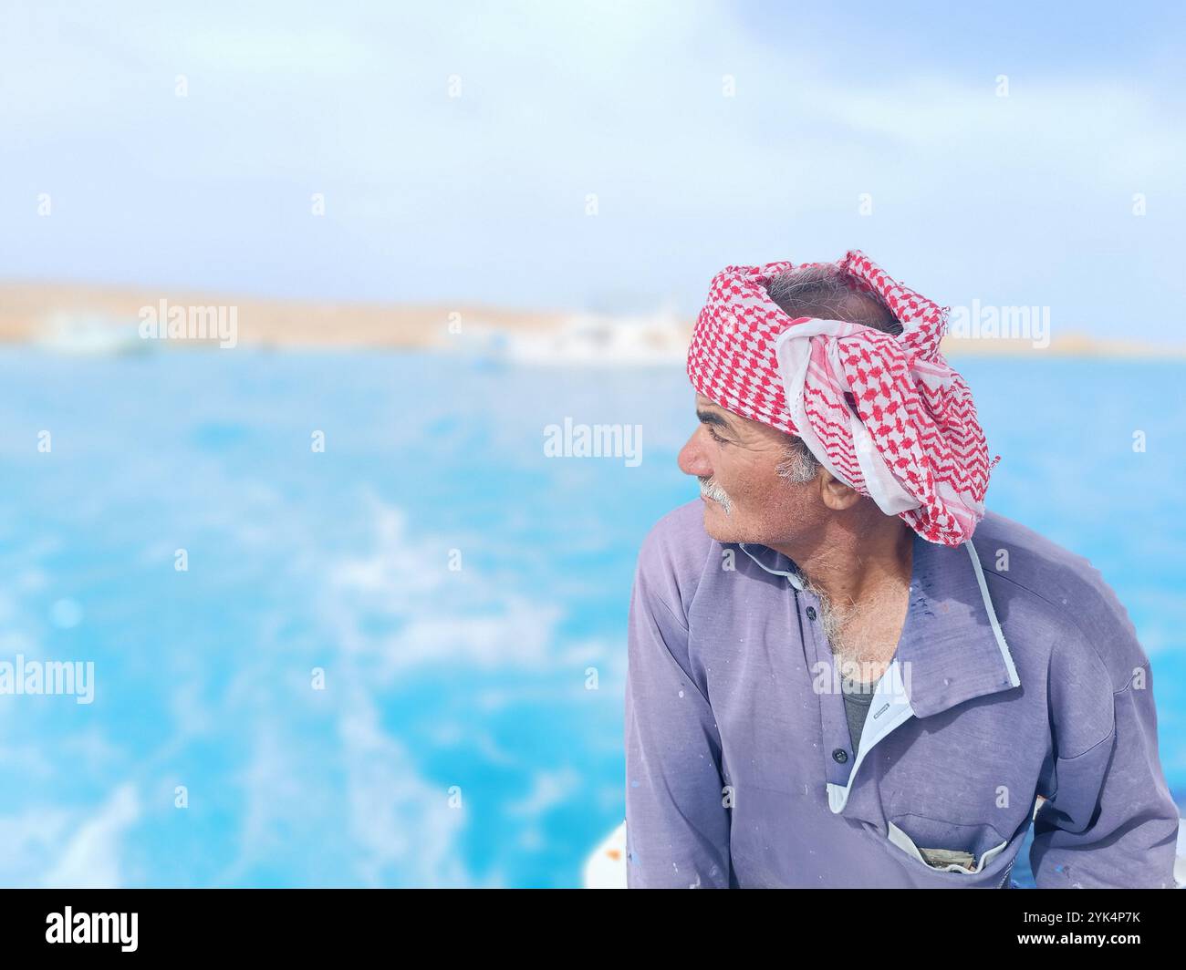 Old Sailor in the Sea Riding and Sailing with HIS Boat un vecchio marinaio con un bianco con baffi bianchi che indossa una sciarpa beduina sulla testa Foto Stock