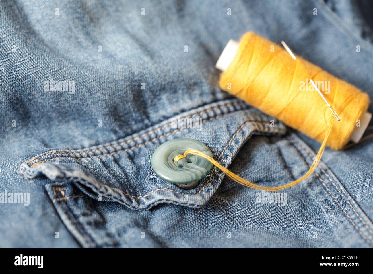 Bottoni, filetto e ago per cucire su denim. Fatto a mano. Primo piano Foto Stock