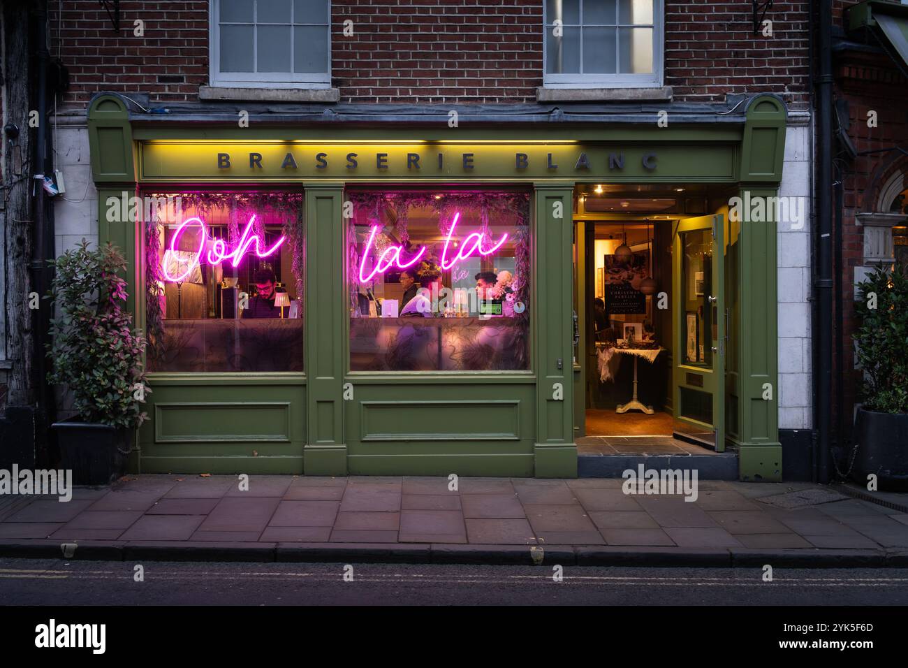 Clienti della Brasserie Blanc di notte con le parole Ooh la la illuminata, un ristorante e bar francese in Jewry Street, Winchester, Regno Unito Foto Stock