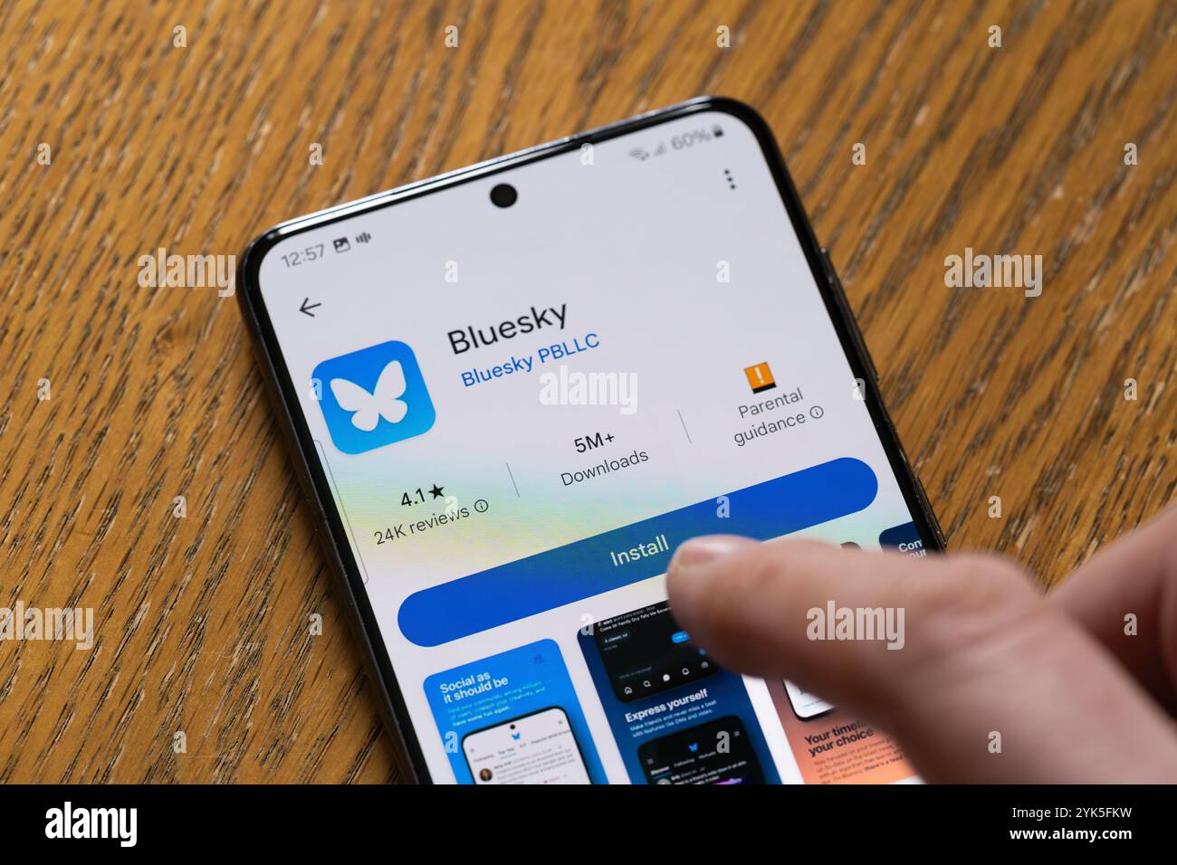 Persona che installa Bluesky su uno smartphone, Regno Unito. Un'app di social media che attrae follower da X. Un progetto finanziato da Twitter con maggiore moderazione Foto Stock