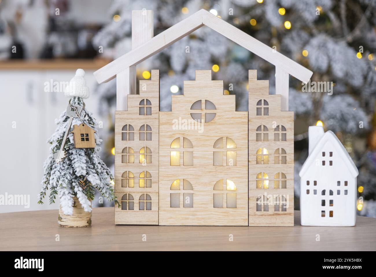 Chiave dell'albero di Natale e piccola casa in una casa intima con decorazioni natalizie sul tavolo della cucina bianca festosa. Regalo per Capodanno. Assicurazione, passaggio a New Foto Stock