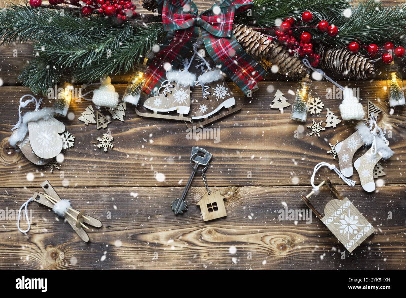 Casa chiave con portachiavi cottage su un ambiente festivo amichevole, sfondo naturale con albero di Natale. Felice anno nuovo-sfondo rosso, regalo, biglietto d'auguri. Foto Stock