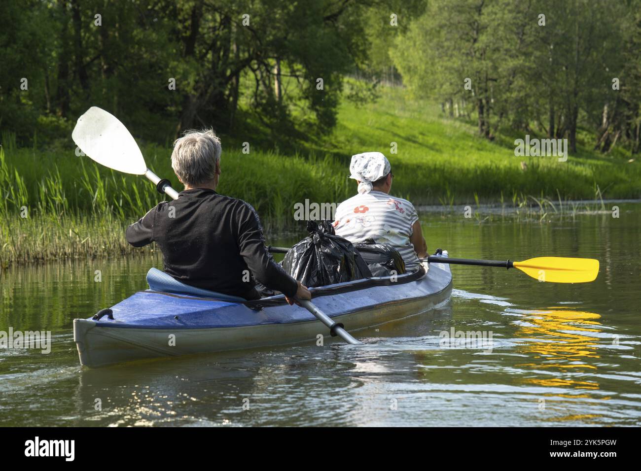 Gita in kayak per tutta la famiglia per il Seigneur e senora. Una coppia di anziani sposati che voga una barca sul fiume, un'escursione in acqua, un'avventura estiva. Sport legati all'età Foto Stock