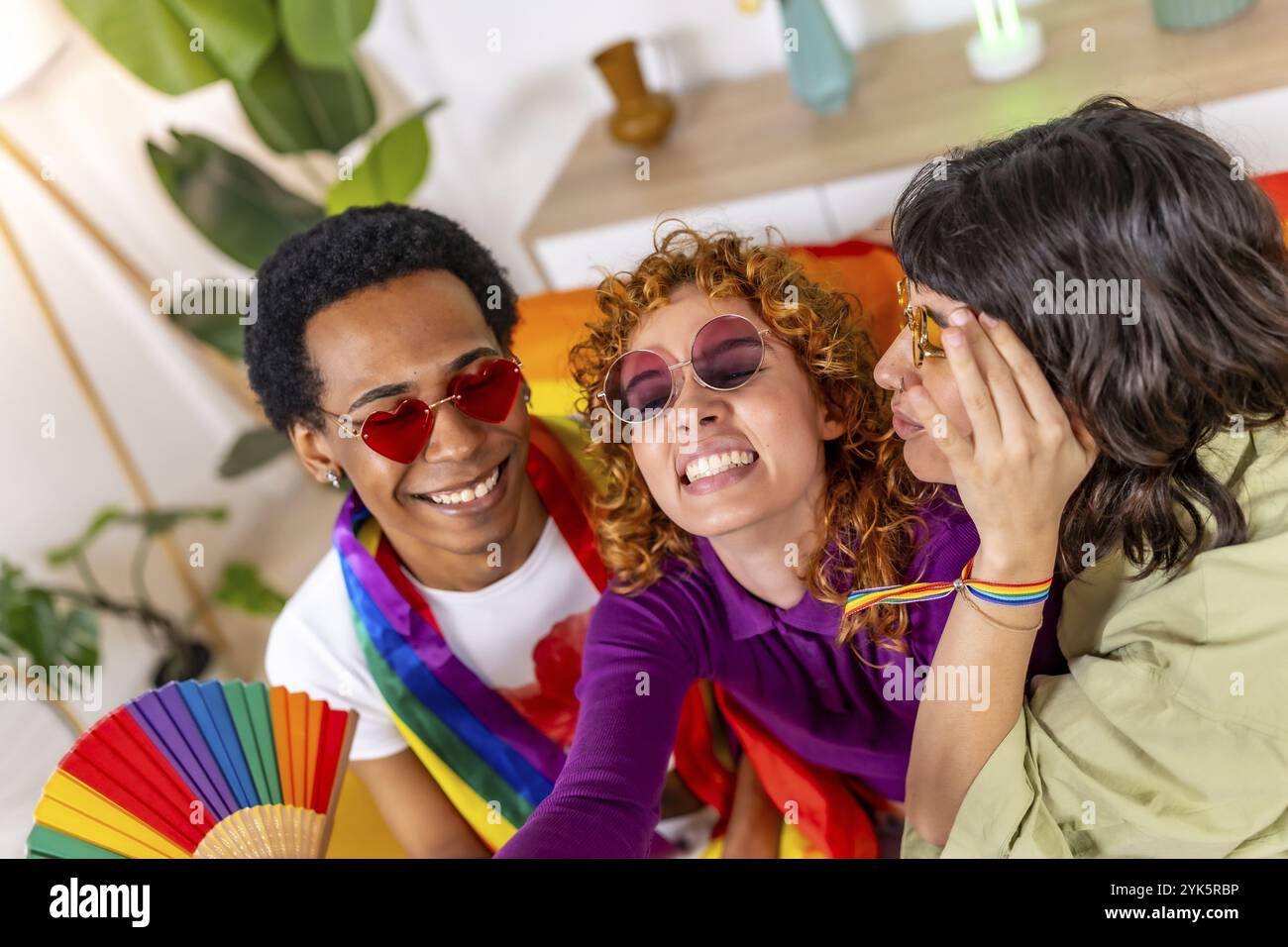 Amici multietnici e non binari che si divertono insieme a celebrare l'orgoglio lgbt a casa Foto Stock