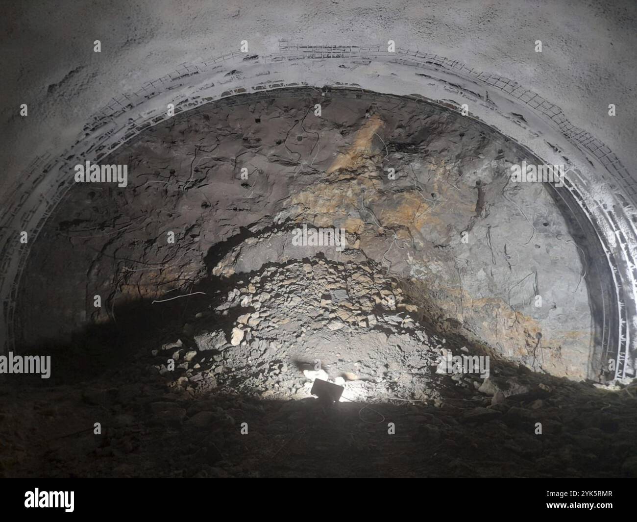 Tunnel sotterraneo che mostra una parete di roccia e dettagli costruttivi con illuminazione soffusa Foto Stock