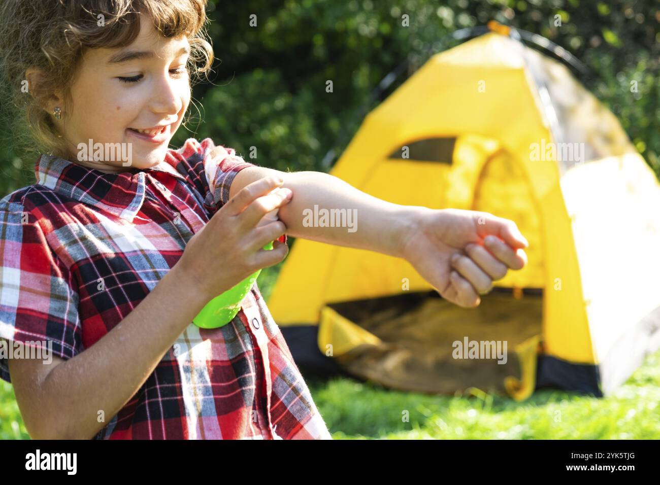 Ragazza spruzza zanzara spray sulla pelle in natura che mordono le mani e i piedi. Protezione da punture di insetti, repellente sicuro per i bambini. Recr. Esterno Foto Stock