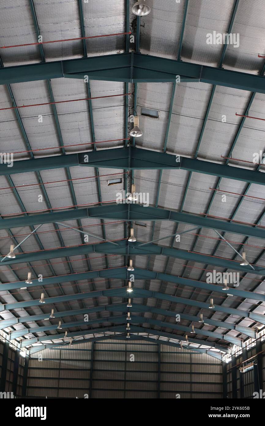Vista dettagliata del soffitto di un magazzino industriale con travi metalliche e lucernari. Foto Stock