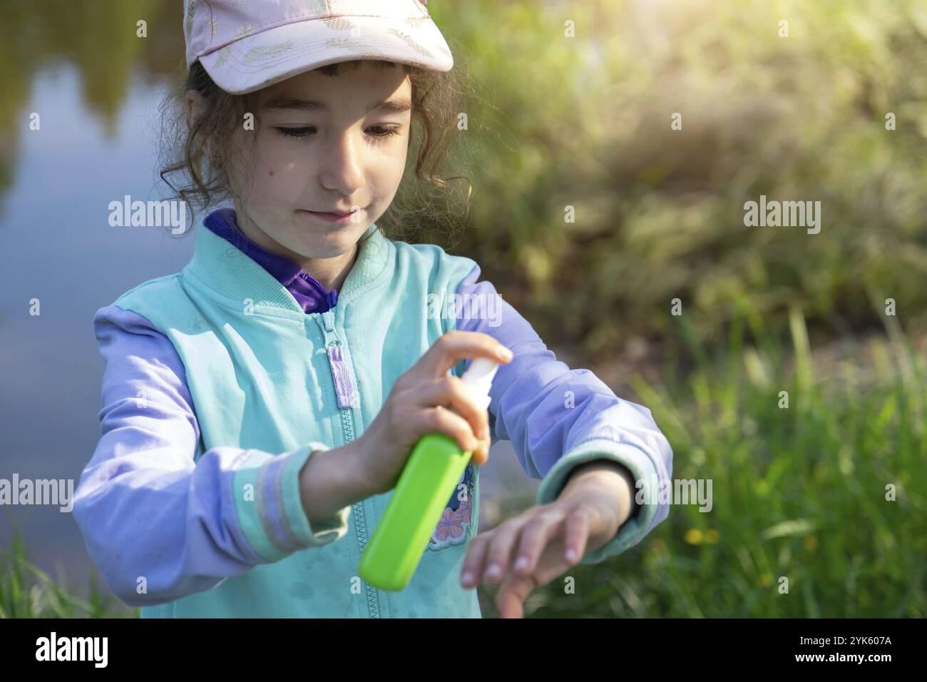 Ragazza spruzza zanzara spray sulla pelle in natura che mordono le mani e i piedi. Protezione da punture di insetti, repellente sicuro per i bambini. Recr. Esterno Foto Stock