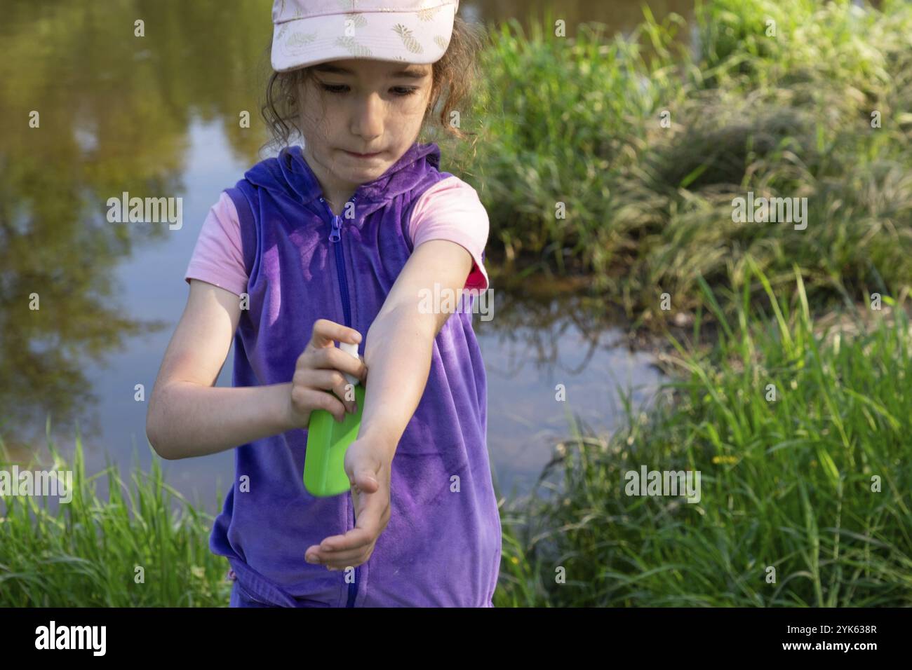 Ragazza spruzza zanzara spray sulla pelle in natura che mordono le mani e i piedi. Protezione da punture di insetti, repellente sicuro per i bambini. Recr. Esterno Foto Stock