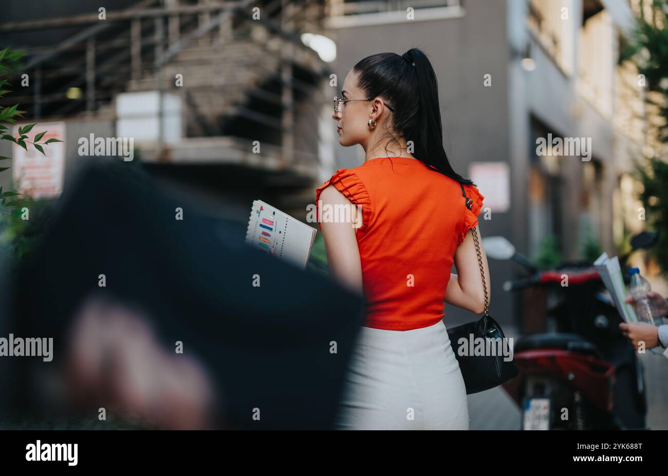 Donna d'affari in cima rossa che tiene documenti sulla strada della città Foto Stock