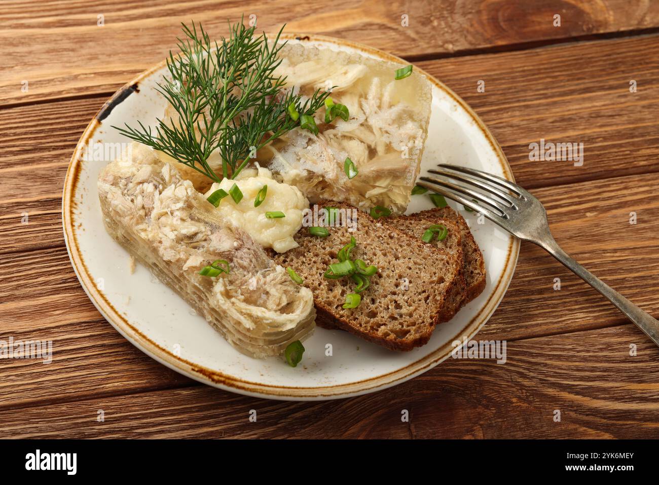 Primo piano porzione di gelatina di carne di pollo aspica o tradizionale dell'Europa orientale con fette di pane di segale e salsa di rafano, su legno marrone Foto Stock