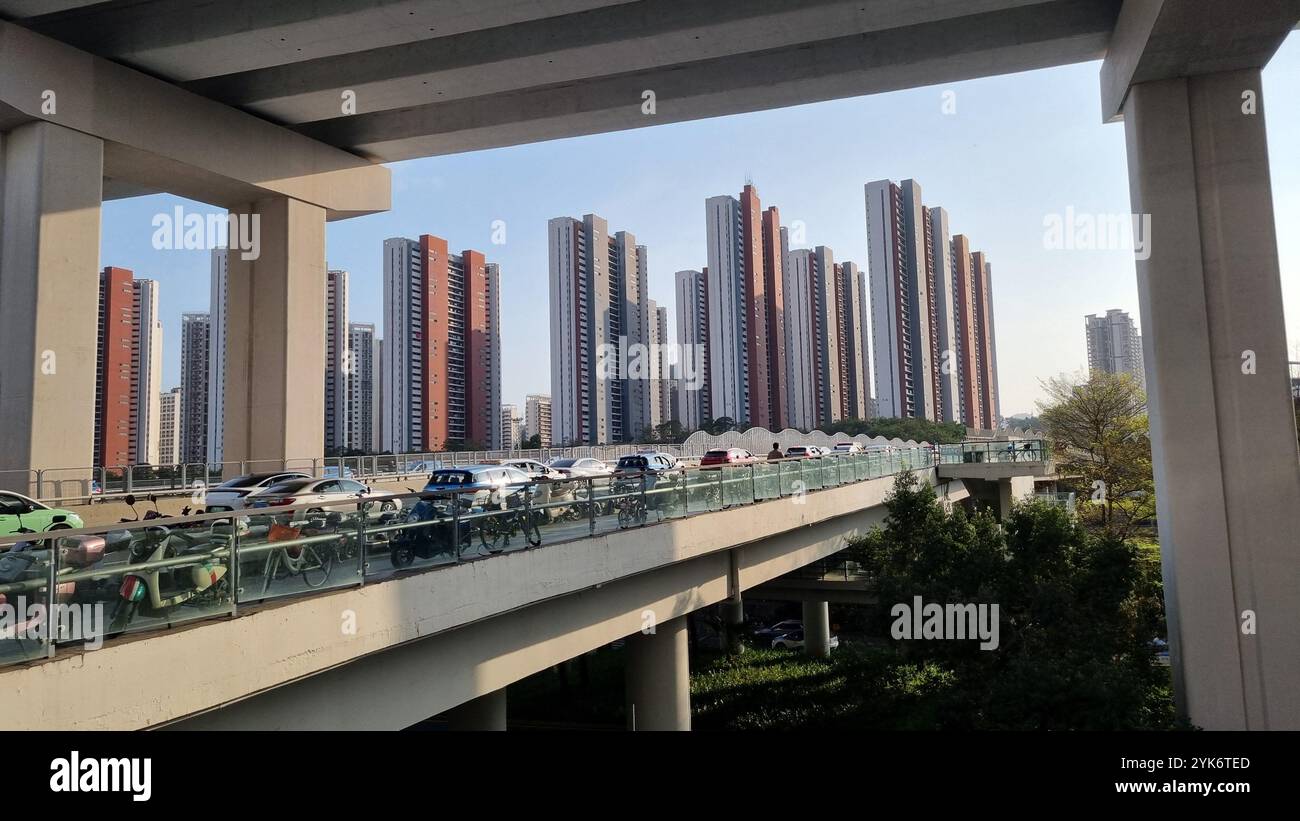 Una scena urbana di Shenzhen, in Cina, che mostra un trafficato cavalcavia con auto e moto sullo sfondo di moderni e alti edifici residenziali. - Immagine stock catturata con smartphone