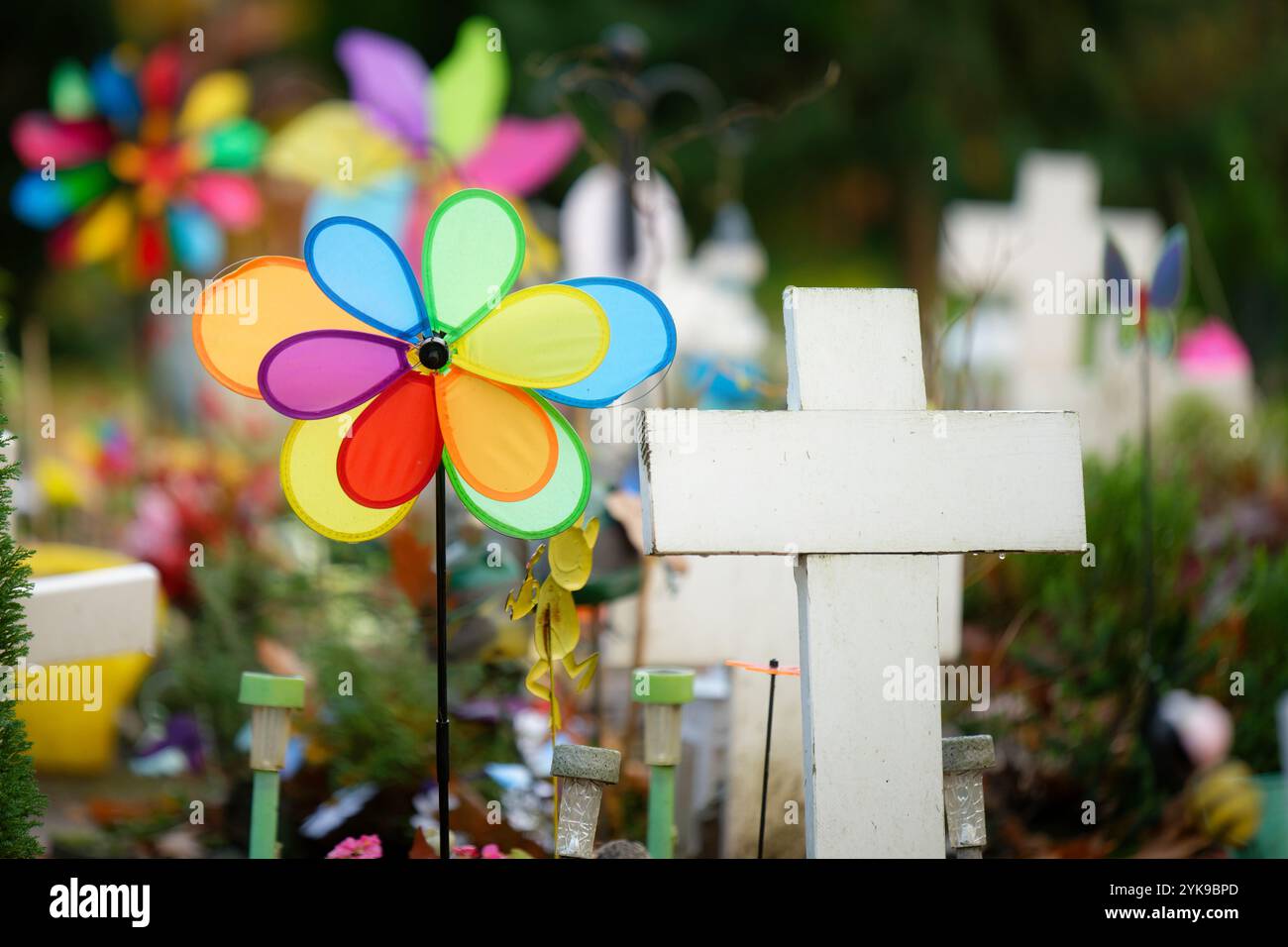 croci bianche e giocattoli colorati in un triste cimitero per bambini Foto Stock
