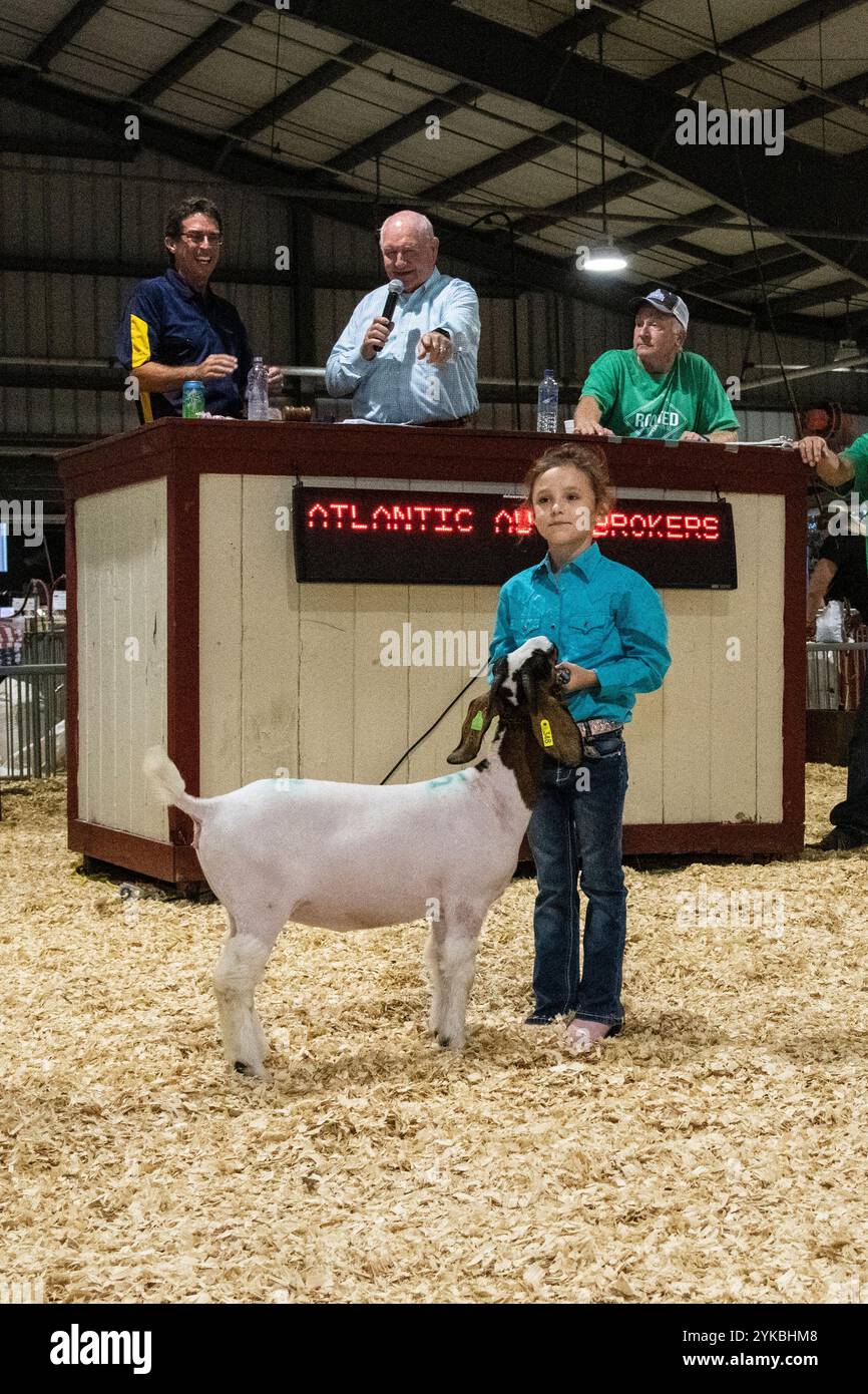 Sonny Perdue, segretario del Dipartimento dell'Agricoltura degli Stati Uniti, parla del futuro dell'agricoltura, mentre Adalyn Lyon mostra la sua capra agli offerenti di bestiame alla fiera statale del Delaware, ad Harrington, DE, il 25 luglio 2019. Il Segretario Perdue e sua moglie Mary Perdue sono in visita alla fiera con il Segretario dell'Agricoltura del Delaware Michael Scuse , che ha mostrato loro mostre FFA e 4-H, ha visitato il fienile del bestiame, si è Unito al Governatore del Delaware John Carney per il disegno della targa, e ha partecipato alla cena del giorno del Governatore, ad Harrington, DE, il 25 luglio 2019. La Delaware State Fair, Inc. È una fiera variegata Foto Stock