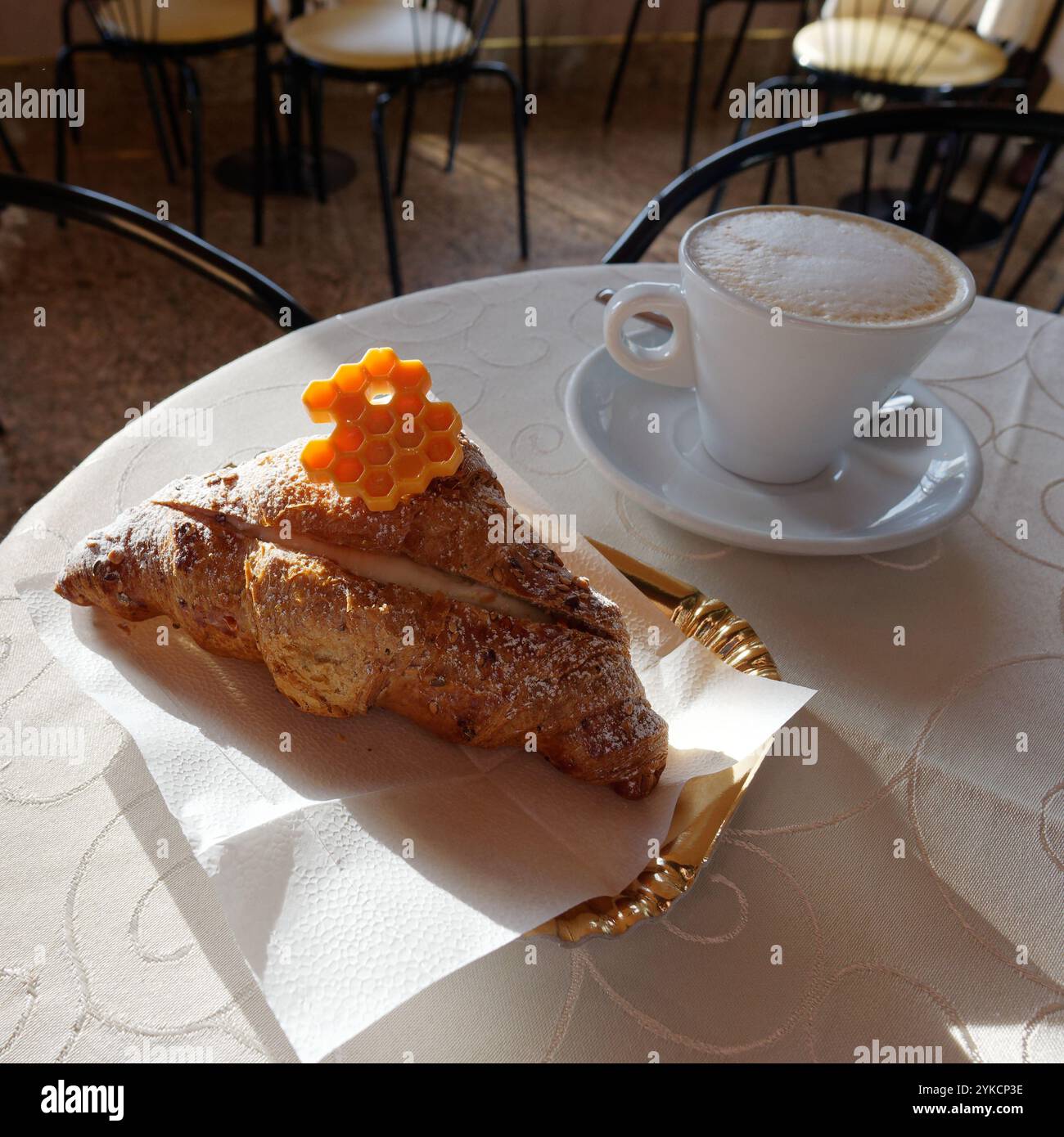 Caffè e croissant con dolce a forma di favo in cima. Montefiascone, Lazio, Italia. 17 novembre 2024 Foto Stock