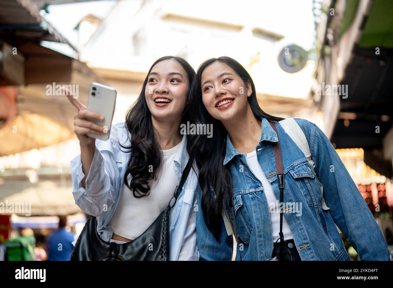 Due belle donne asiatiche emozionate amano esplorare insieme un mercato locale in una città del sud-est asiatico, divertendosi durante il loro viaggio in Thailandia. vacanze estive Foto Stock