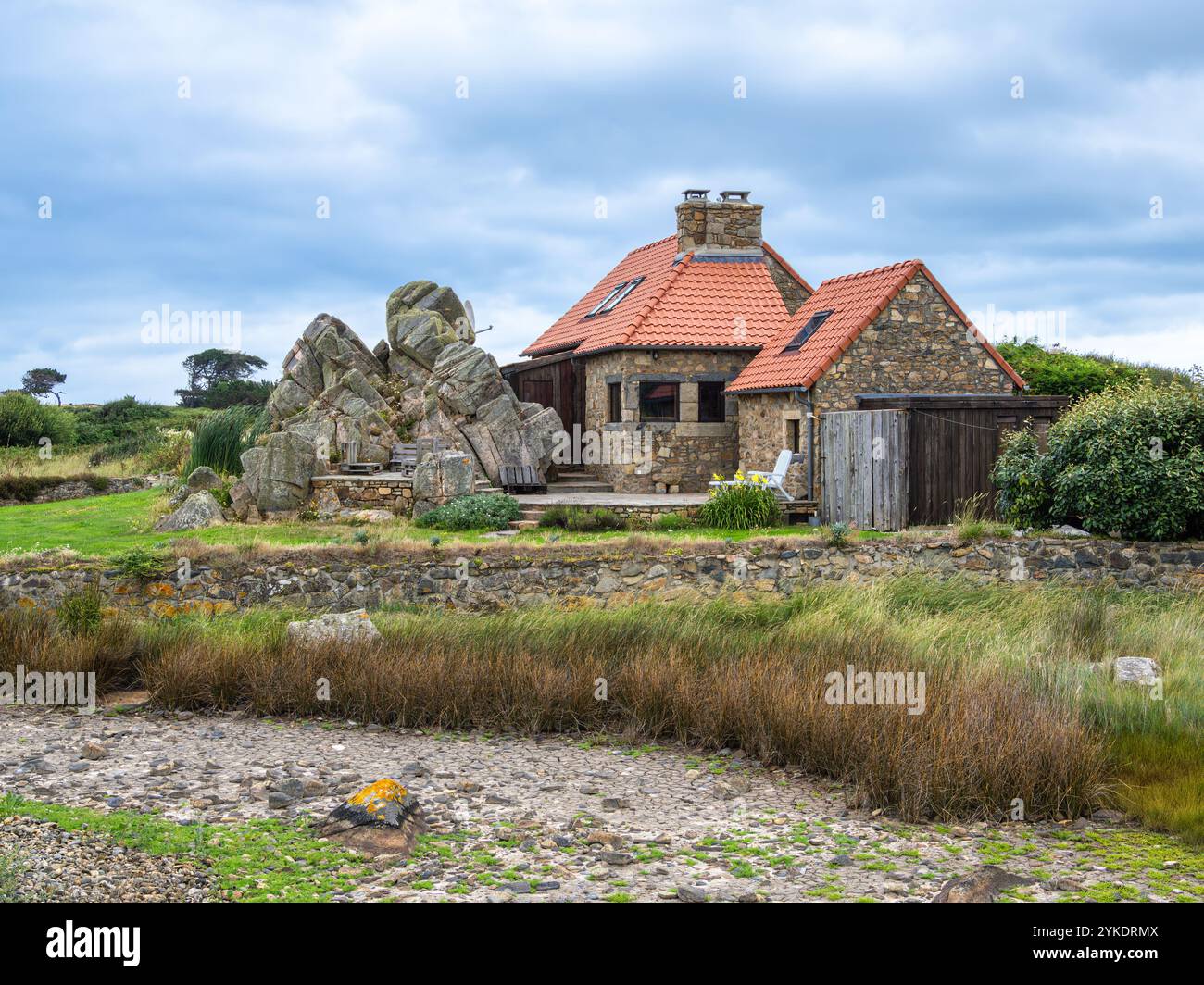 Plougrescant, Francia - 22 luglio 2024: Incantevole casa bretone per vacanze a Plougrescant, Bretagna, circondata da rocce e vegetazione Foto Stock