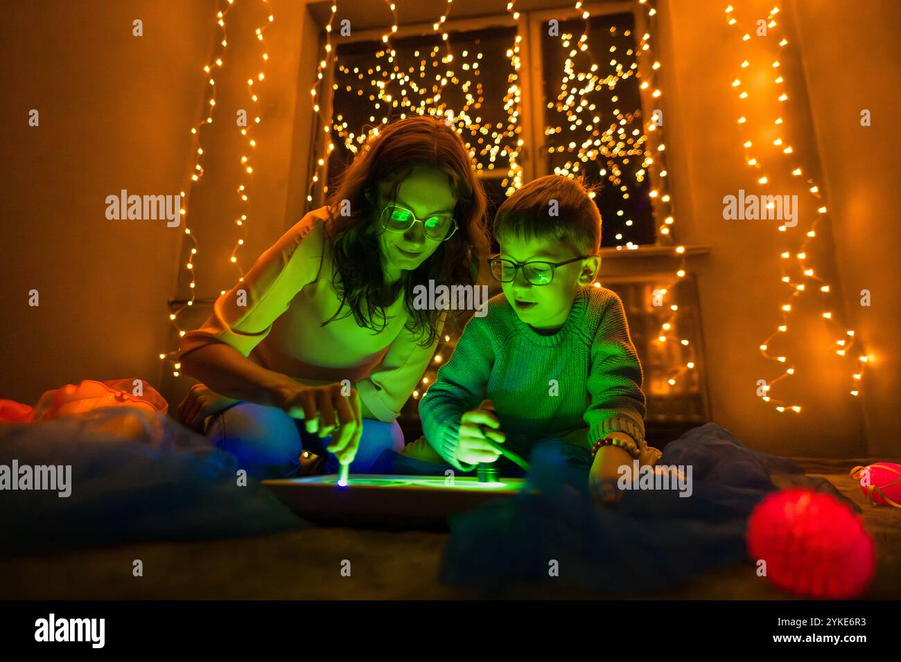 Bambino e terapista in camera stimolante sensoriale, Black snoezelen. Bambino autistico che gioca con il terapista durante la sessione di terapia occupazionale. Foto Stock