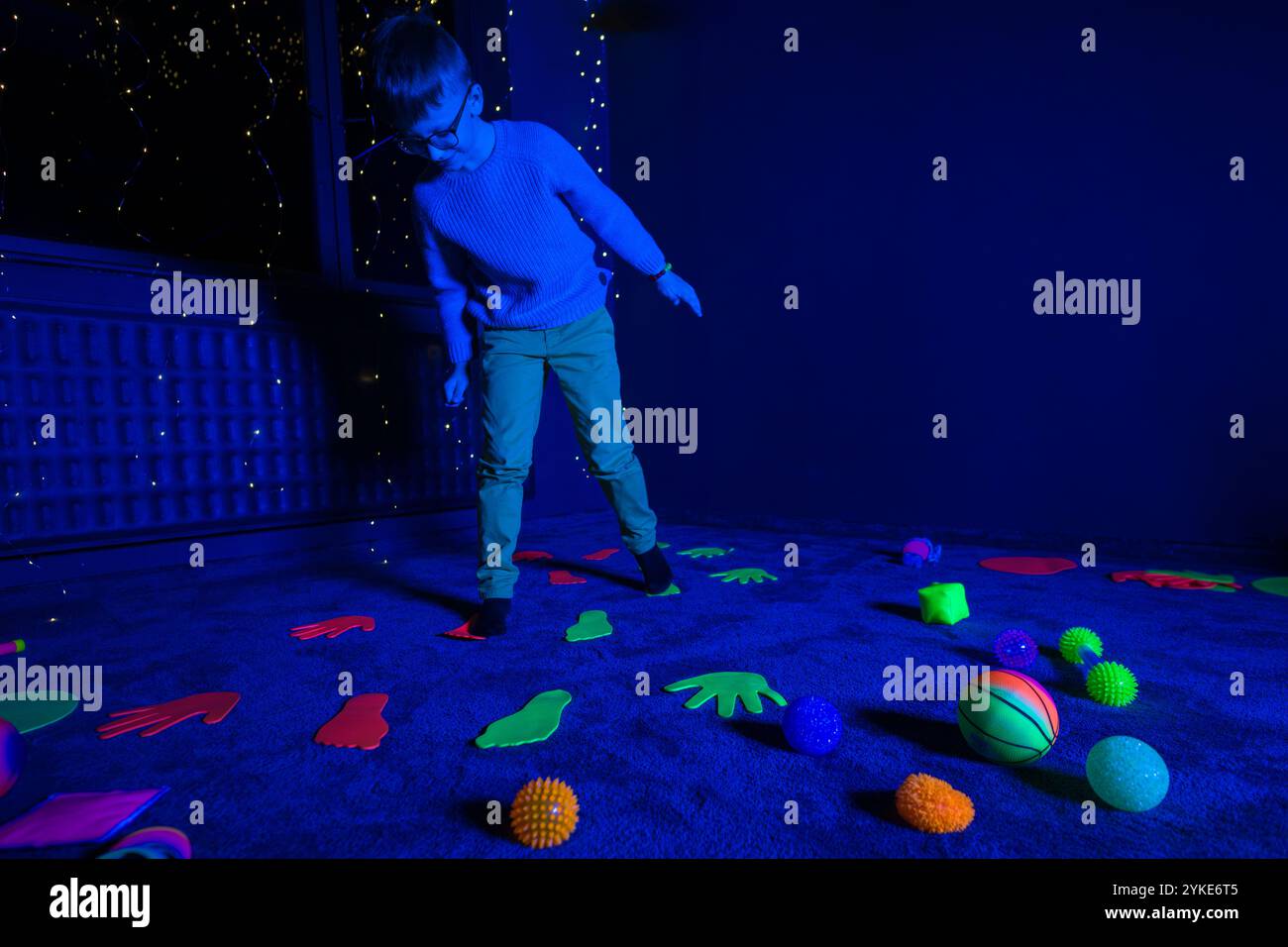 Bambino in sala terapia stimolante sensoriale, nero snoezelen. Bambino autistico che gioca durante la sessione di terapia. Terapia occupazionale. Stimolo sensoriale terapeutico Foto Stock