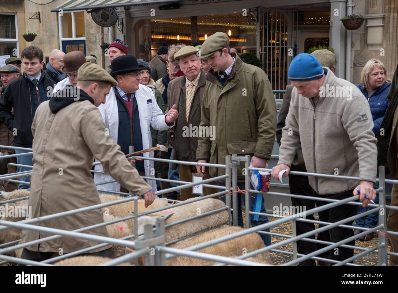 Agricoltore britannico con le sue pecore in piedi nella penna. Il responsabile del collocamento che estrae un’offerta da un rappresentante di uno dei due macellai/acquirenti locali per gli allevatori di ovini che si trovano nelle recinzioni temporanee. L'annuale Christmas Livestock Show, il mercato iSQUARE n Uppingham, Rutland, Inghilterra 24 novembre 2021 2020s HOMER SYKES Foto Stock