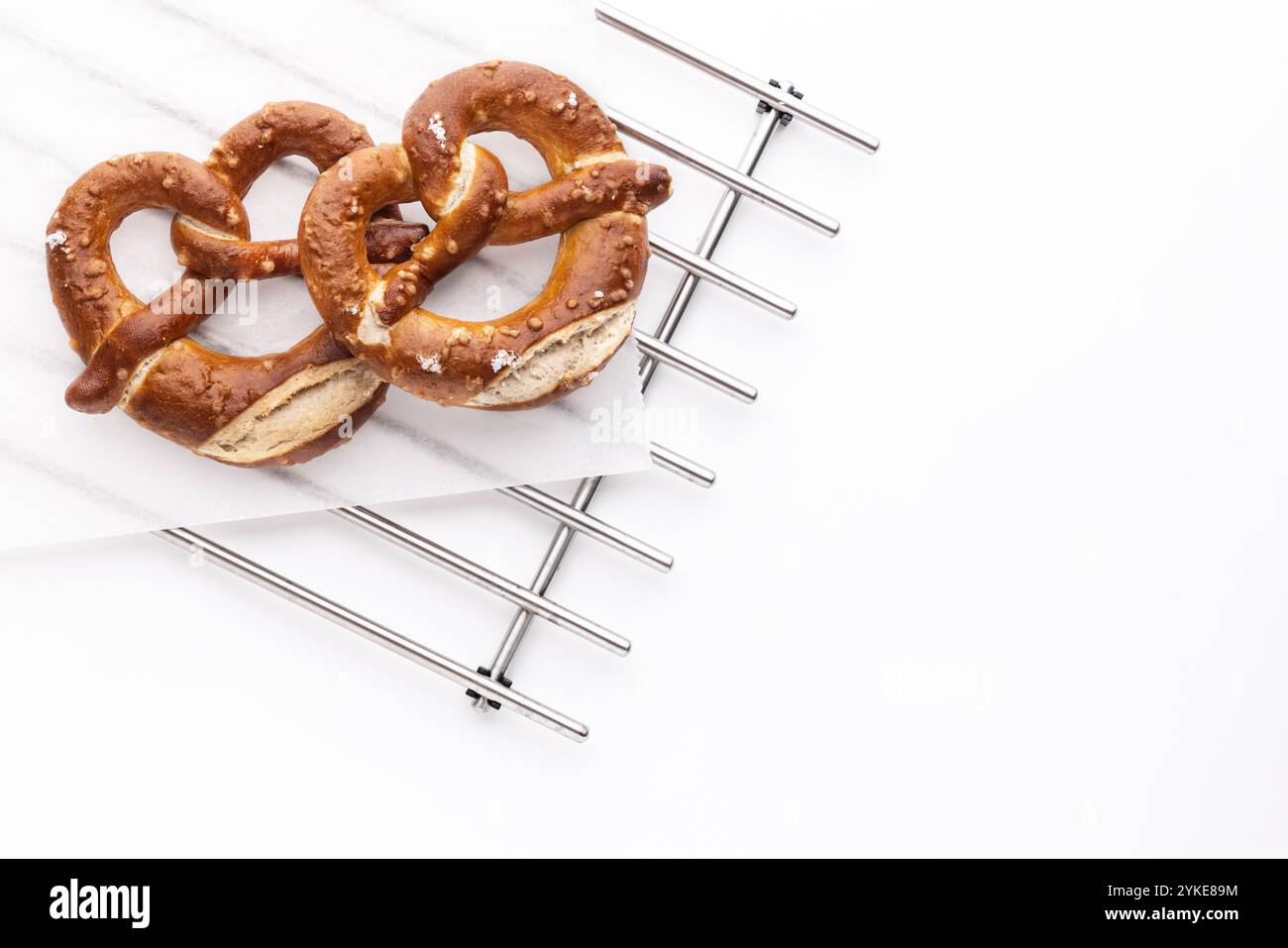 Pretzel di pane appena sfornati su una griglia in metallo fresco su sfondo bianco Foto Stock