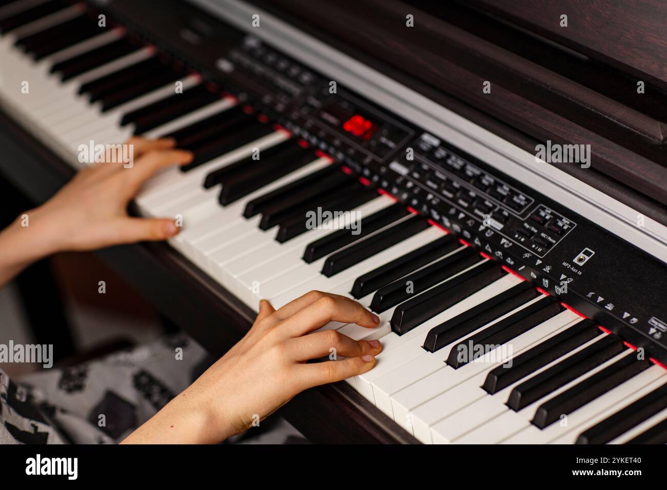 Immagine ravvicinata delle mani del bambino che suonano il pianoforte digitale a casa Foto Stock
