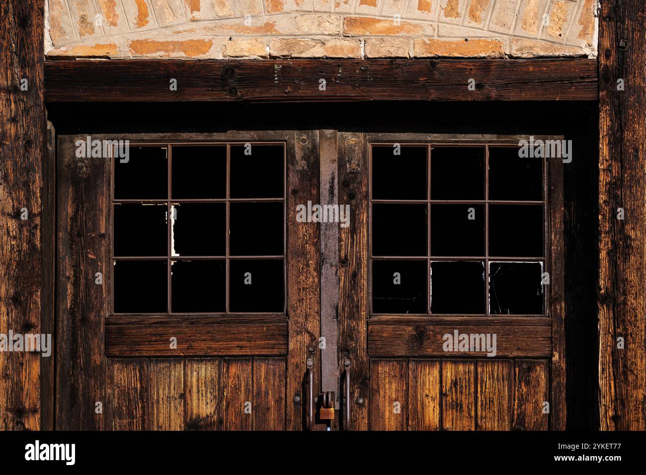 Vecchia porta in legno con finestre di vetro rotte di un magazzino industriale abbandonato come sfondo Foto Stock