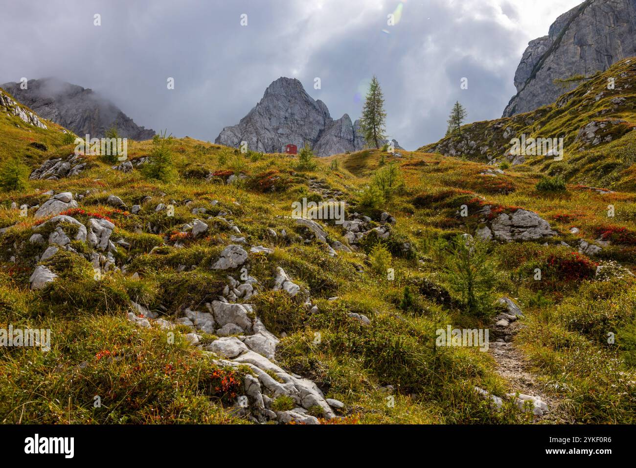 Rifugio alpino bivaco situato in un aspro terreno alpino. Rifugio rosso bivacco nelle Dolomiti. Struttura compatta contro paesaggi mozzafiato Foto Stock