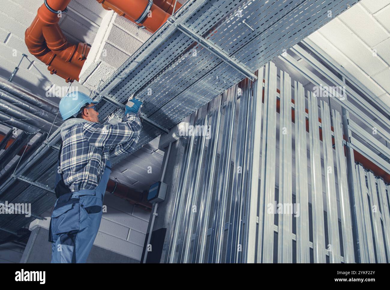 Un operaio edile si concentra sull'installazione di strutture metalliche sopra, garantendo stabilità strutturale in un nuovo edificio. L'ambiente è industriale A. Foto Stock