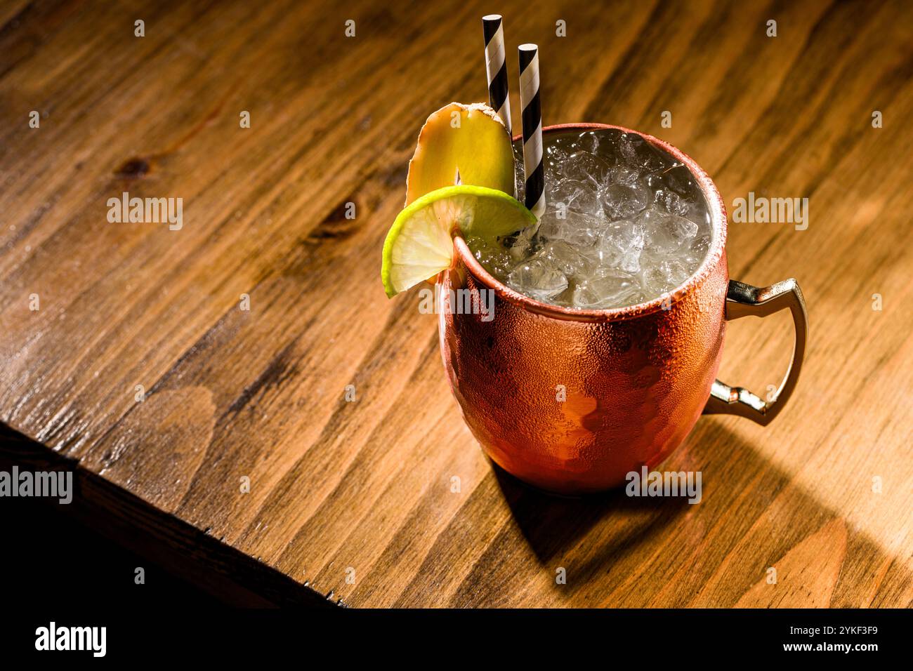 Un classico mulo di Mosca servito in una tradizionale tazza di rame su un rustico tavolo di legno. La bevanda è decorata con una fetta di lime, con ghiaccio tritato e st Foto Stock