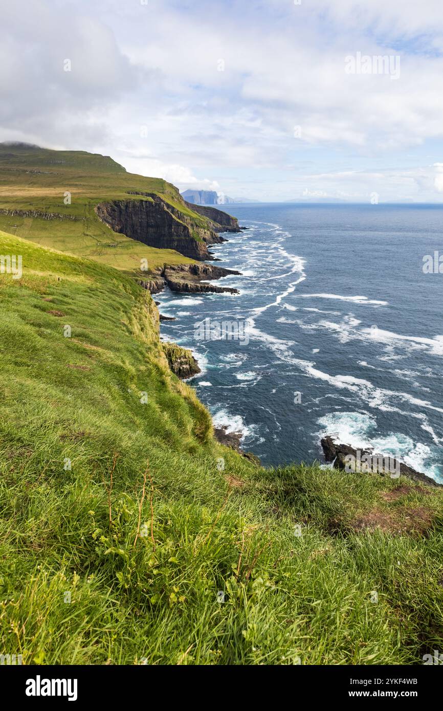 Paesaggio costiero erboso e roccioso con scogliere nell'Oceano Atlantico settentrionale escursioni turistiche, escursioni a piedi e gite naturalistiche nelle Faroes Foto Stock