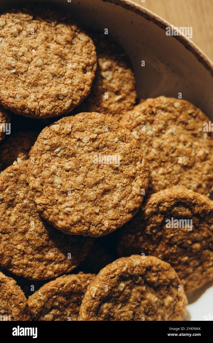 Biscotti fatti in casa a grani interi, cotti senza zucchero, disposti in un recipiente di ceramica su una superficie di legno. Foto Stock