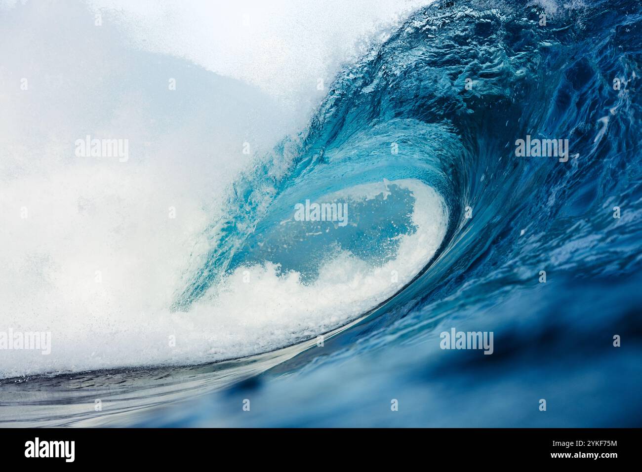 Un'immagine straordinaria cattura una potente onda oceanica che si arriccia maestosamente, mettendo in mostra la bellezza e la forza della natura con vivaci sfumature blu e movem dinamico Foto Stock