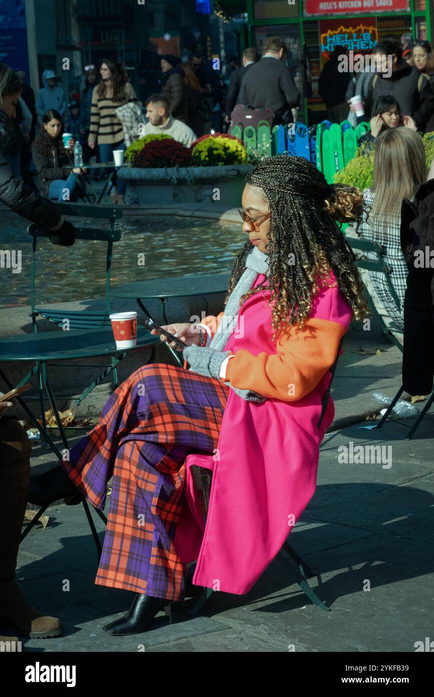 Foto sincera di una donna di mezza età con un guardaroba colorato e lunghe estensioni. A Bryant Park, nel centro di Manhattan. Foto Stock