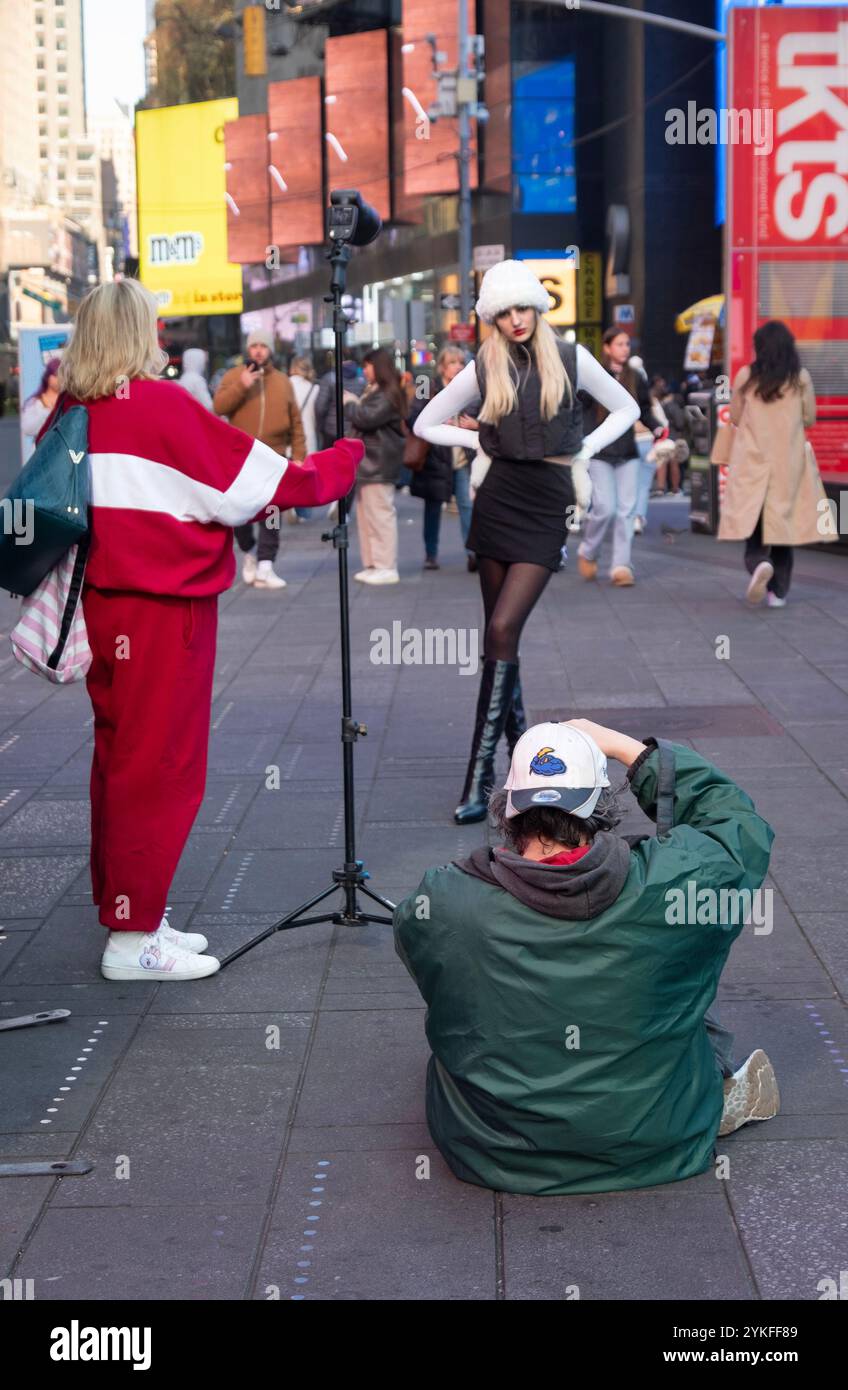 Un fotografo e il suo assistente scattano abiti invernali su un modello piuttosto sottile. Vicino alle scale rosse di Times Square, Manhattan, New York. Foto Stock