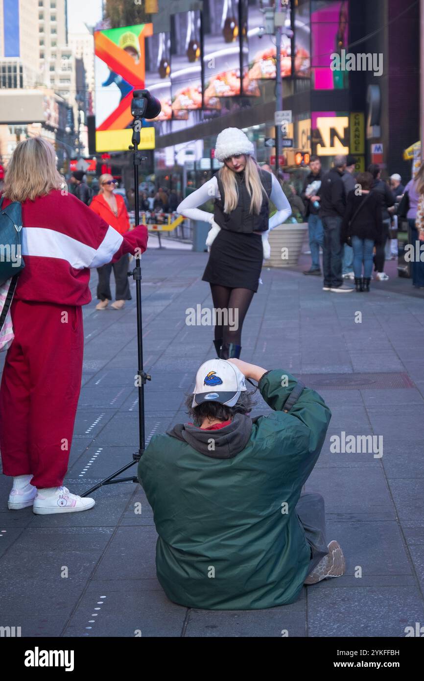 Un fotografo e il suo assistente scattano abiti invernali su un modello piuttosto sottile. Vicino alle scale rosse di Times Square, Manhattan, New York. Foto Stock