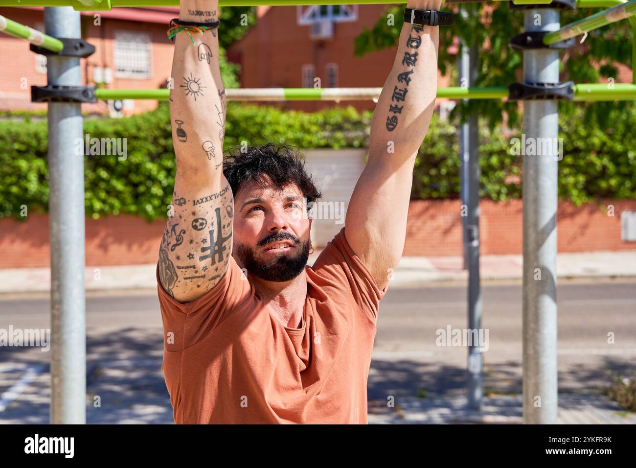 Un uomo si impegna in una vigorosa sessione di allenamento in un parco calistenico all'aperto, dimostrando forza, determinazione e dedizione al fitness fisico Foto Stock