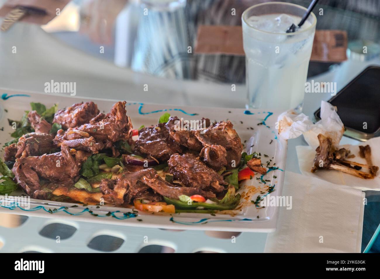Galiña di Palu – ragù di iguana – è servito al ristorante Blue View Sunset Terrace a Westpunt, Curaçao. Il piatto è considerato una prelibatezza tradizionale dell’isola. Le ossa rosicchiate sul tovagliolo accanto mostrano che la carne viene staccata dall’osso prima di essere mangiata. Foto Stock
