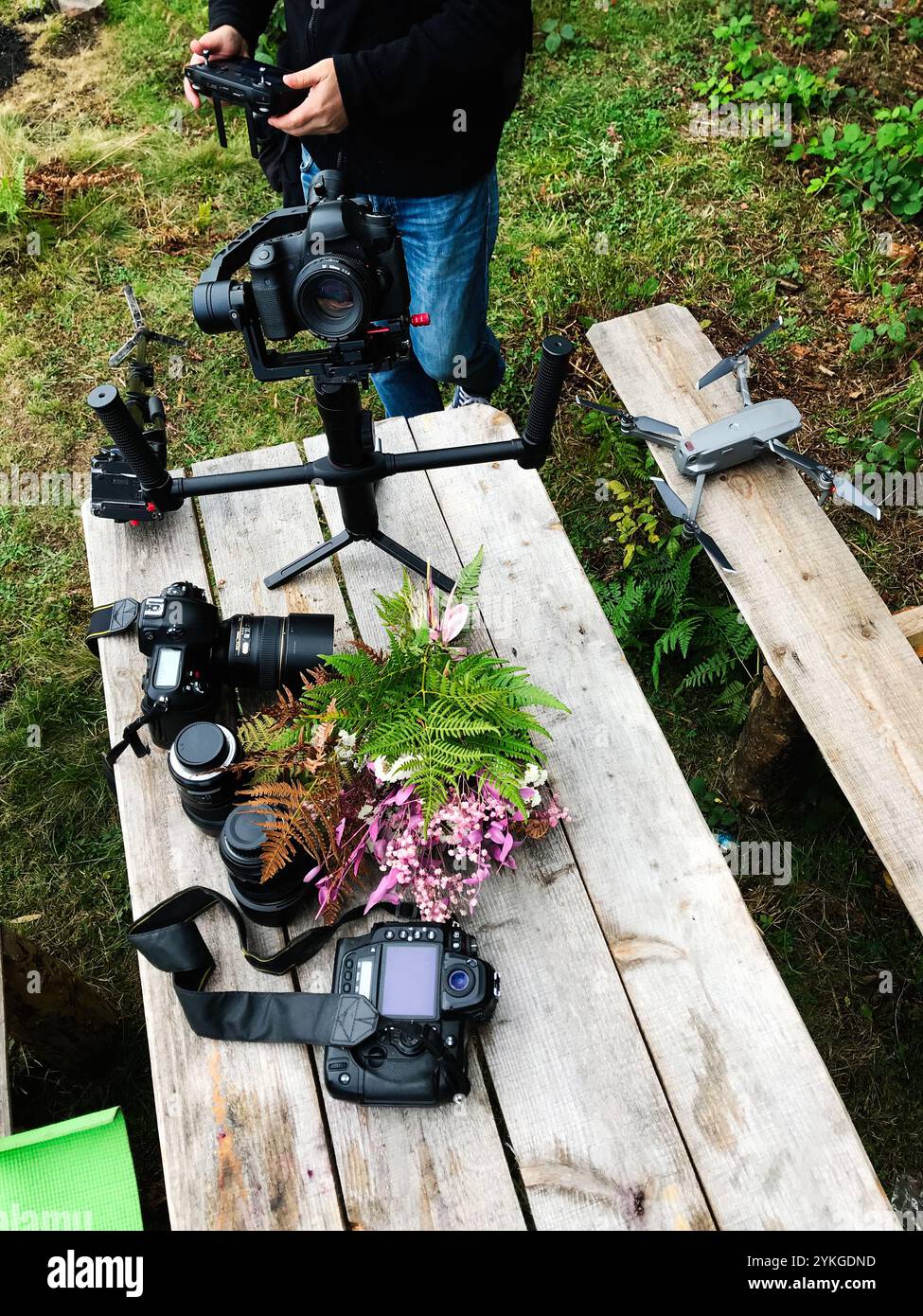 Scena all'aperto con una collezione di attrezzature fotografiche professionali, tra cui fotocamere, obiettivi, drone e treppiede. Ideale per catturare natu Foto Stock