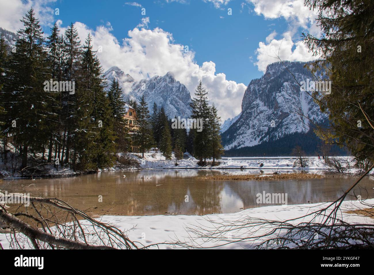 Il laghetto di Dobbiaco racchiuso tra pinete e. le cime innevate delle dolomiti Foto Stock