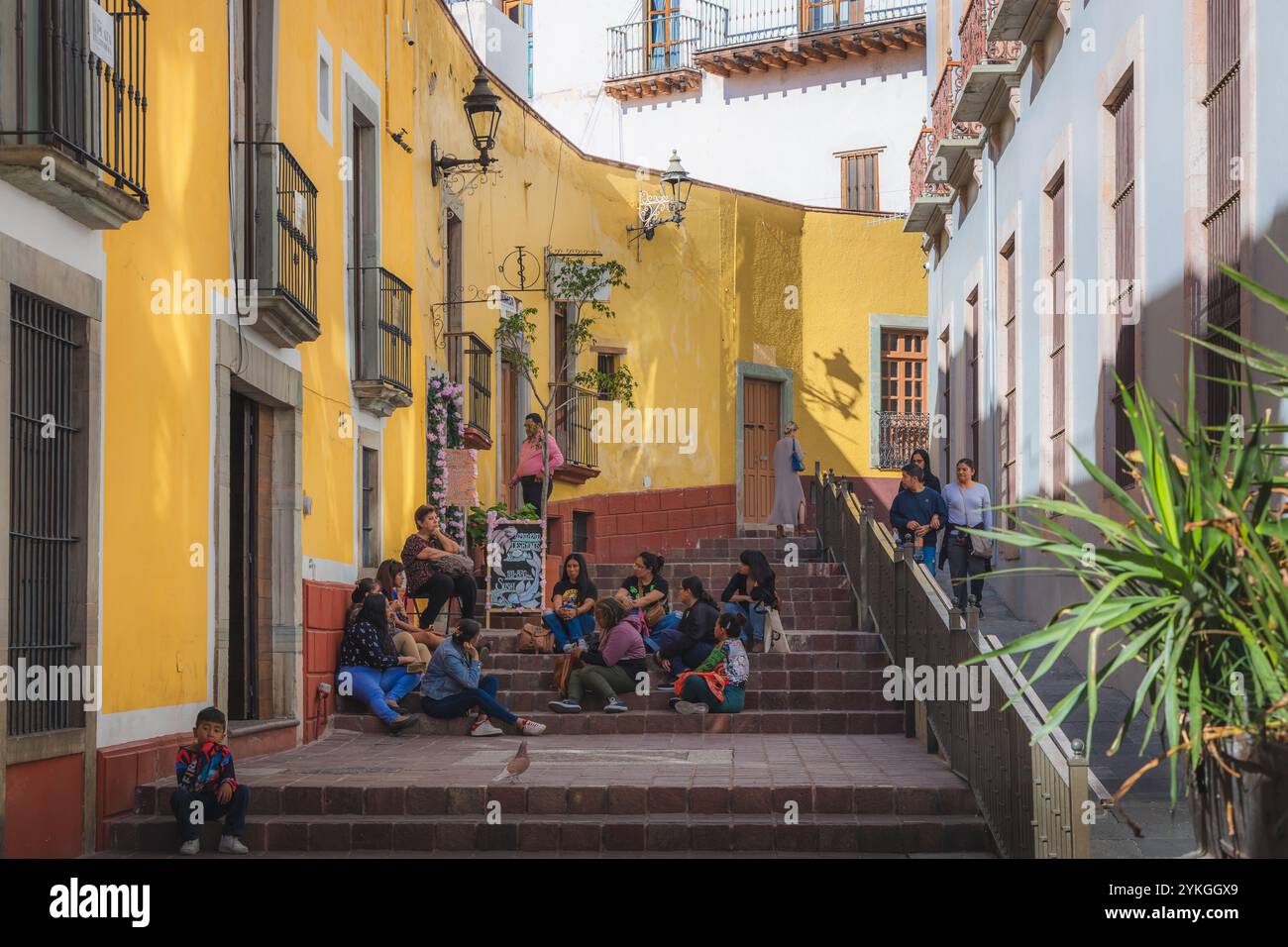 Guanajuato, Messico - 9 febbraio 2024: Un gruppo di abitanti del posto si rilassa e socializza su gradini colorati nella storica città vecchia di Guanajuato, circondata da vibran Foto Stock