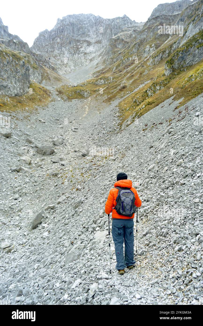 Un uomo guarda il grido sotto la cima mentre si trova su un sentiero escursionistico nella valle di Ljubokuć, noto anche come Lugo i kuq (Prokletije, Montenegro) Foto Stock