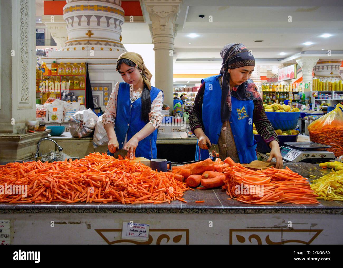 Taglio di bastoncini di carote fresche come ingredienti per Plov, il piatto nazionale del Tagikistan nel mercato di Mehrgon, Dushanbe, Tagikistan. Foto Stock
