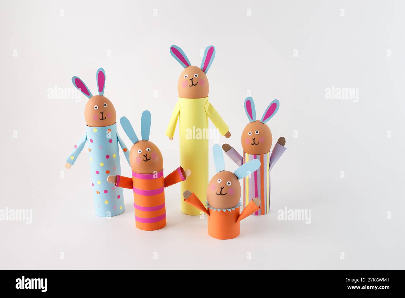 cinque conigli fatti a mano realizzati con tubi di cartone e decorati con carta colorata. Ogni coniglietto ha una testa a forma di uovo con tratti facciali disegnati Foto Stock