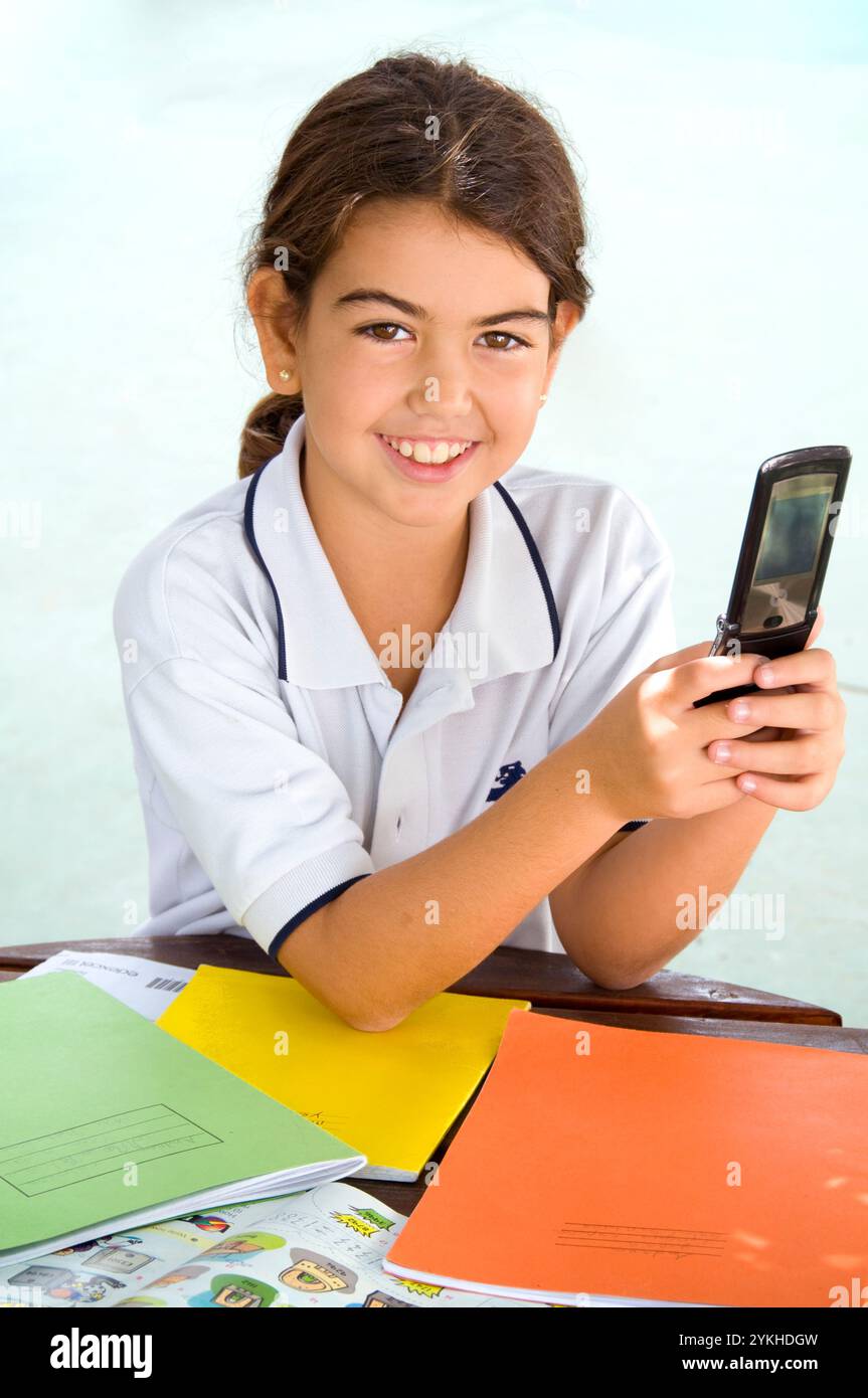 Cellulare studentessa degli anni '2000 studentessa degli anni '9-12 pausa studio in un parco giochi scolastico soleggiato utilizza il suo cellulare Motorola Razr Flip per inviare messaggi di testo Foto Stock