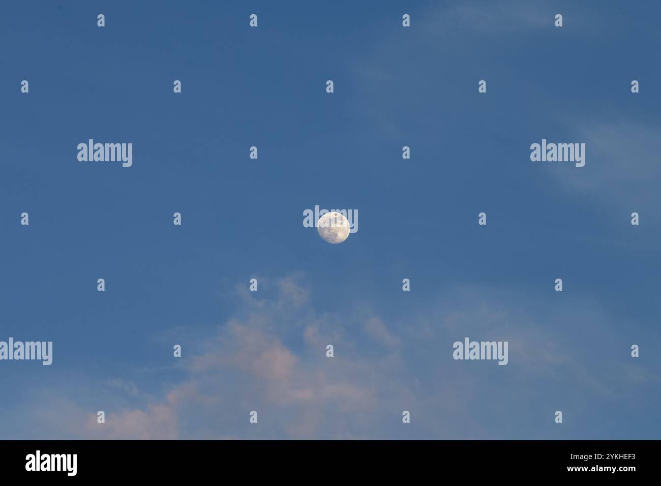 Luna piena nel cielo blu, con nuvole, in una giornata luminosa. Foto Stock