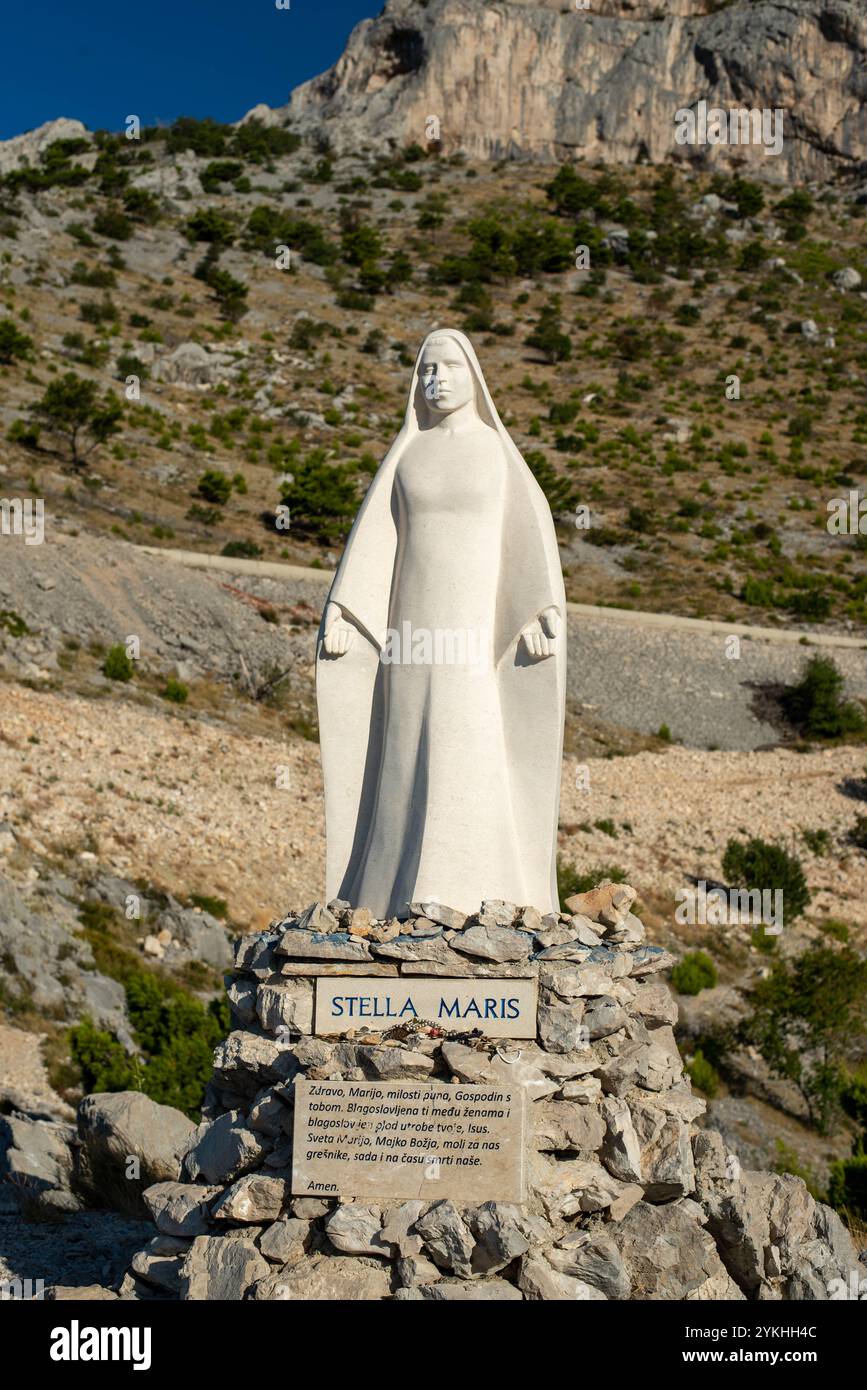 Statua della Vergine Maria sulle montagne croate, con una targa di preghiera "Ave Maria" circondata dalla natura. Foto Stock